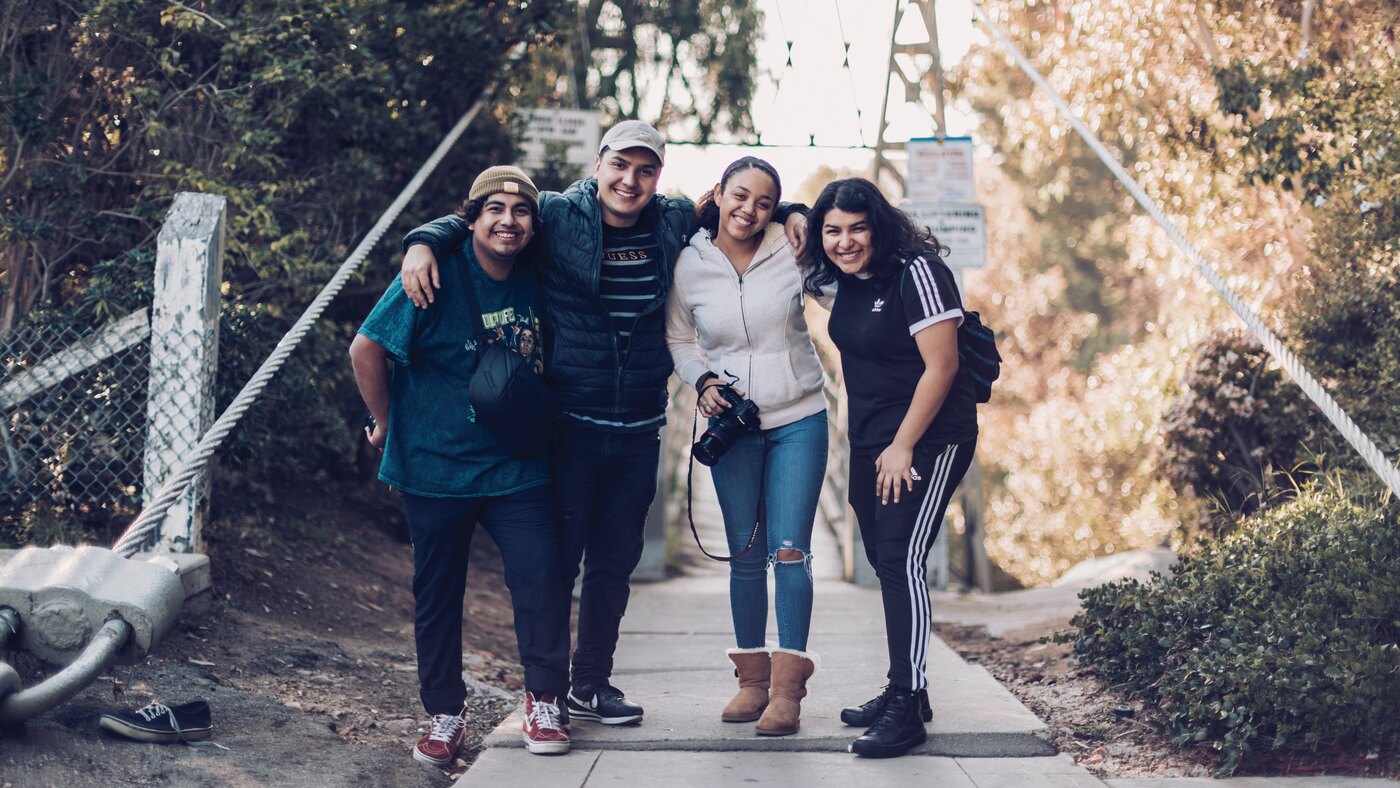 Four young people on a footbridge, smiling
